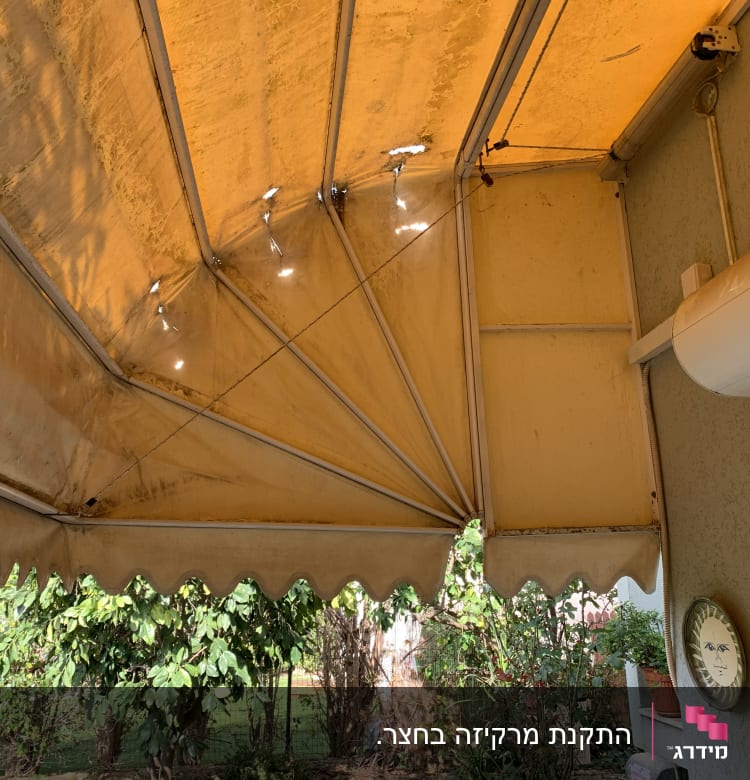 סוכך צהוב עם קרעים קטנים ותמיכה מתכתית
